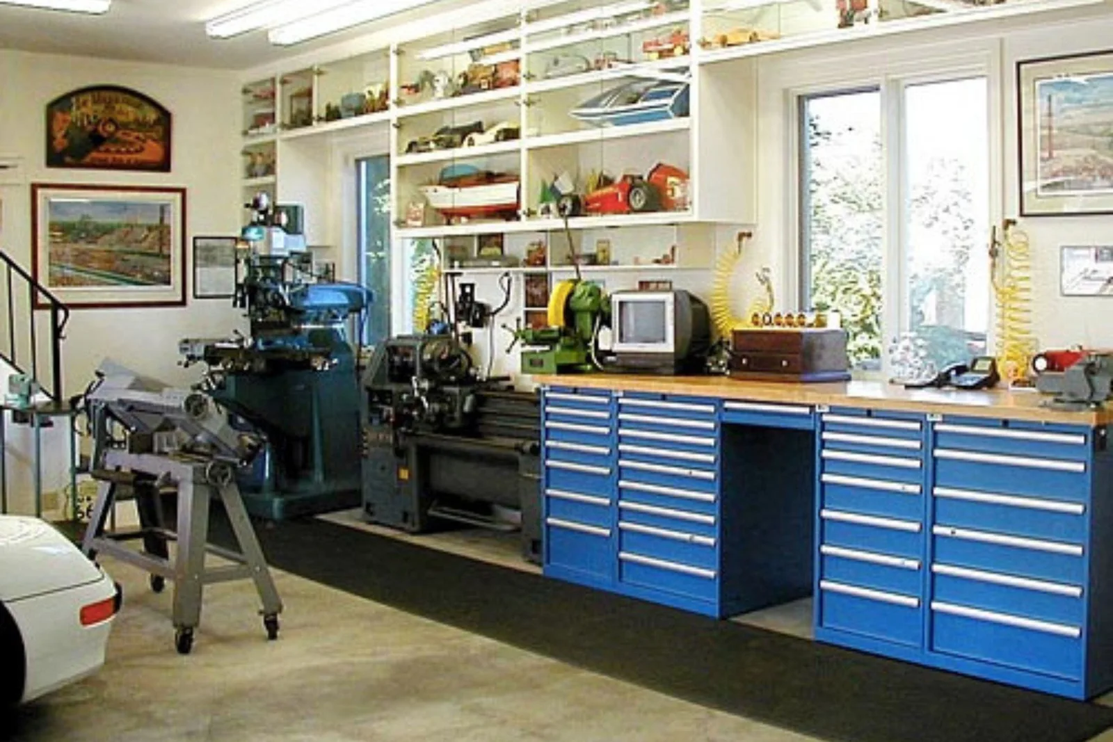 meticulously organized garage workshop with a black rubber runner mat placed in front of a blue workbench and a large lathe. The durable workshop flooring protects the concrete and provides a comfortable anti-fatigue surface for a standing work area.