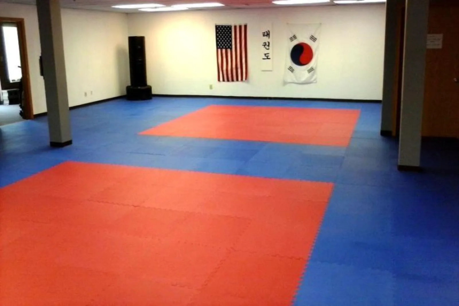 Interlocking foam tiles in a red and blue pattern create a cushioned and safe martial arts studio flooring solution for grappling and striking practice.