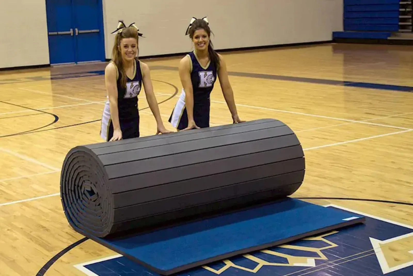 Roll-out cheer mat or carpet-topped flexible foam mat in blue and gray, demonstrating a portable, cushioned surface for gymnastics, cheerleading, and tumbling practice.