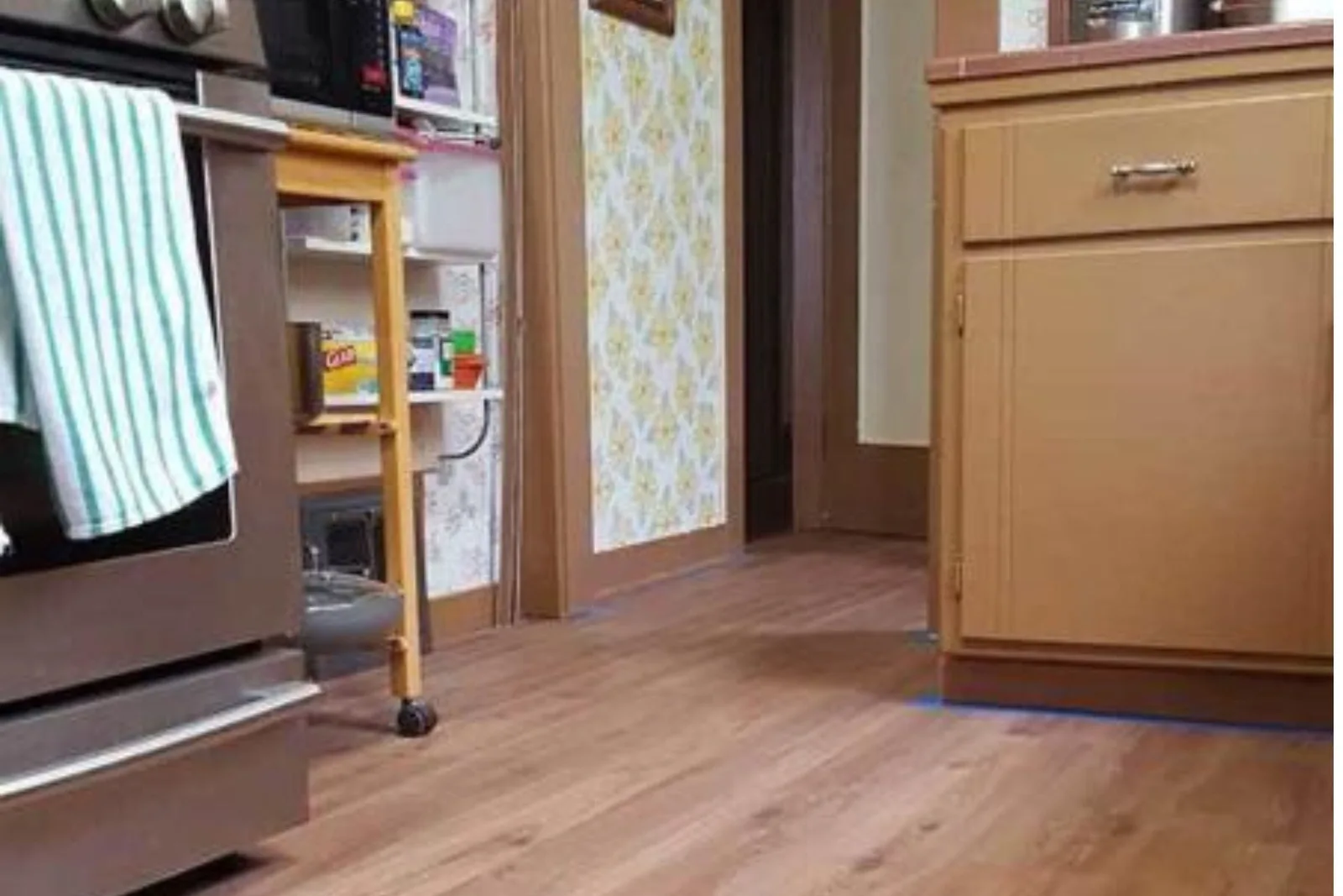 Kitchen and hallway with durable medium wood-look vinyl plank flooring, a water-resistant and easy-to-clean alternative for a residential space.