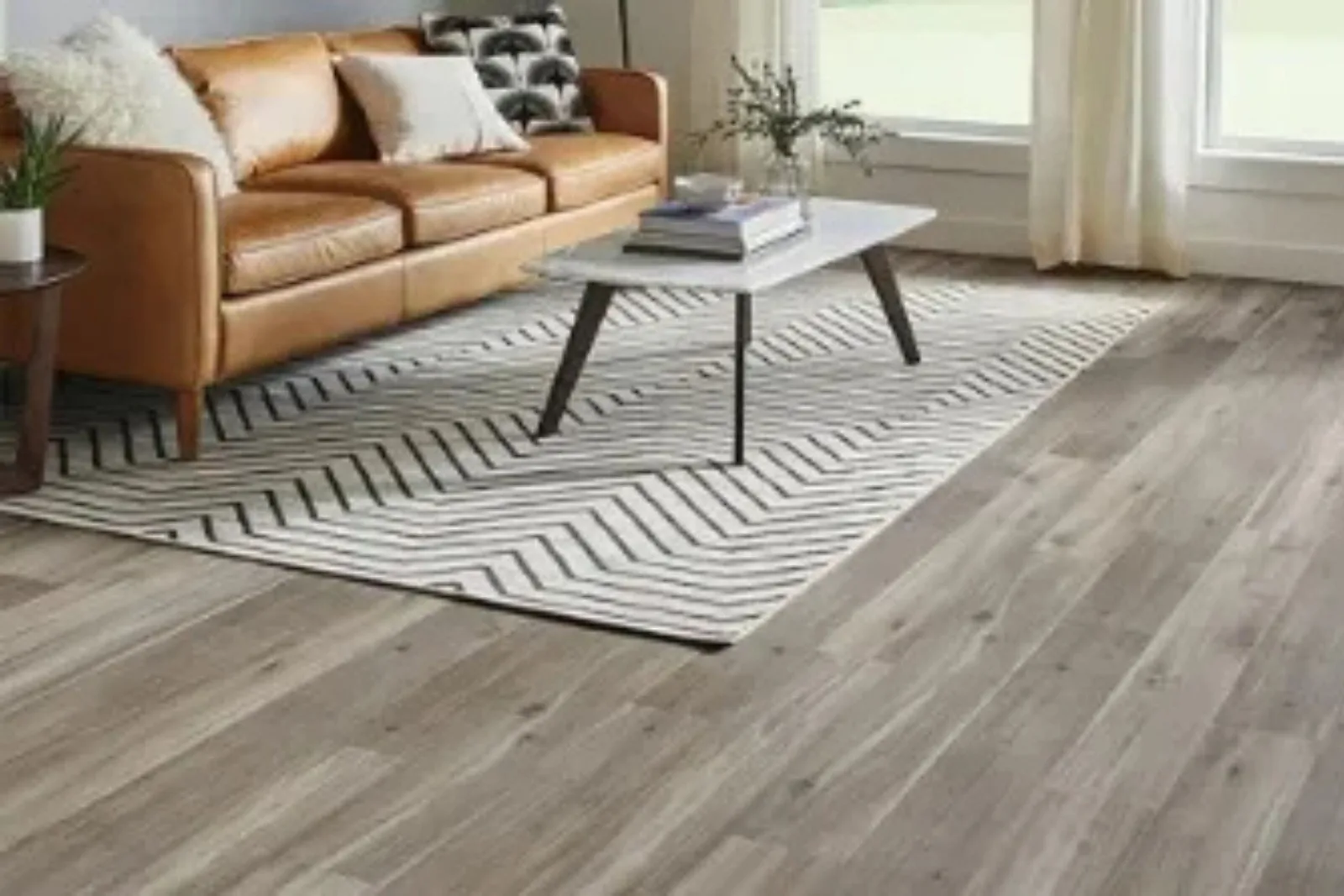 Modern living room with durable gray wood-look vinyl plank flooring and a leather couch, a stylish and low-maintenance alternative to hardwood.