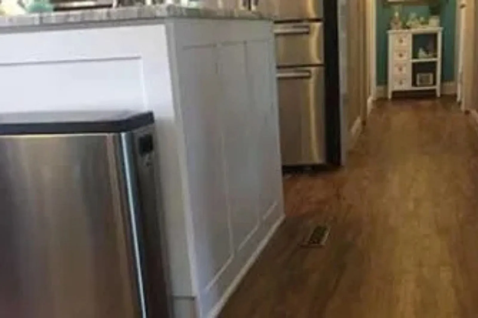 Kitchen and hallway with durable medium wood-look vinyl plank flooring, a water-resistant and easy-to-clean alternative for busy residential spaces.