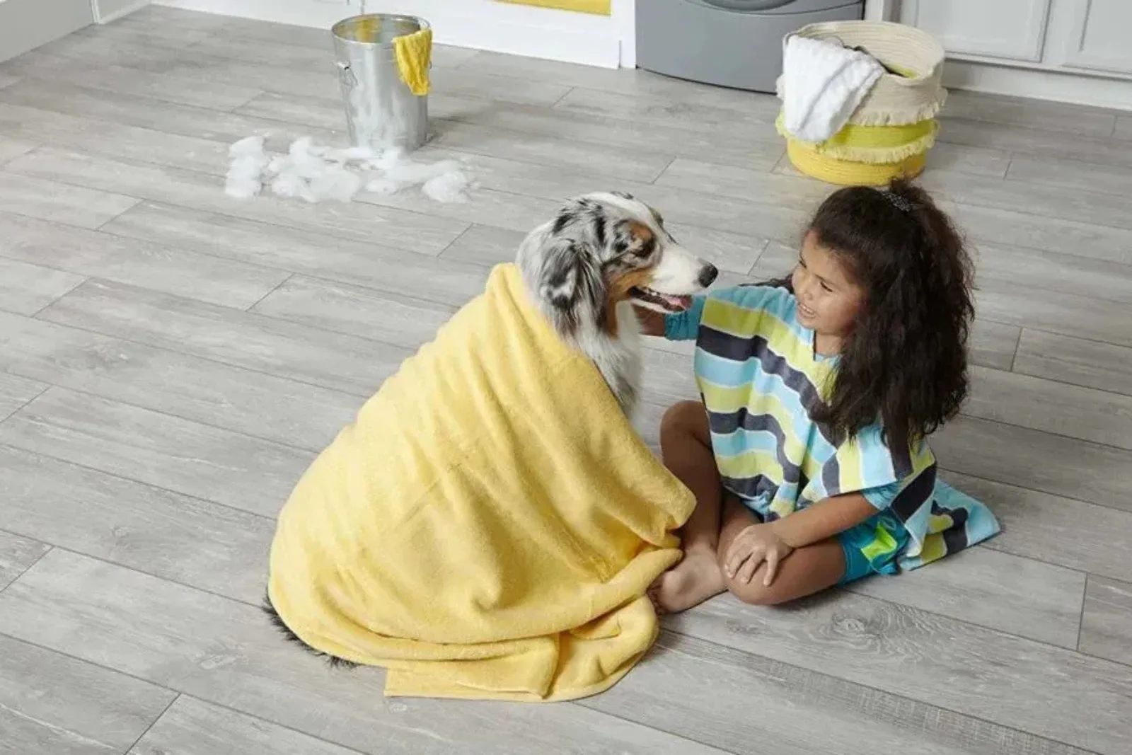 Girl and a dog on durable light gray wood-look vinyl plank flooring, a water-resistant and scratch-resistant alternative to hardwood, perfect for homes with pets.