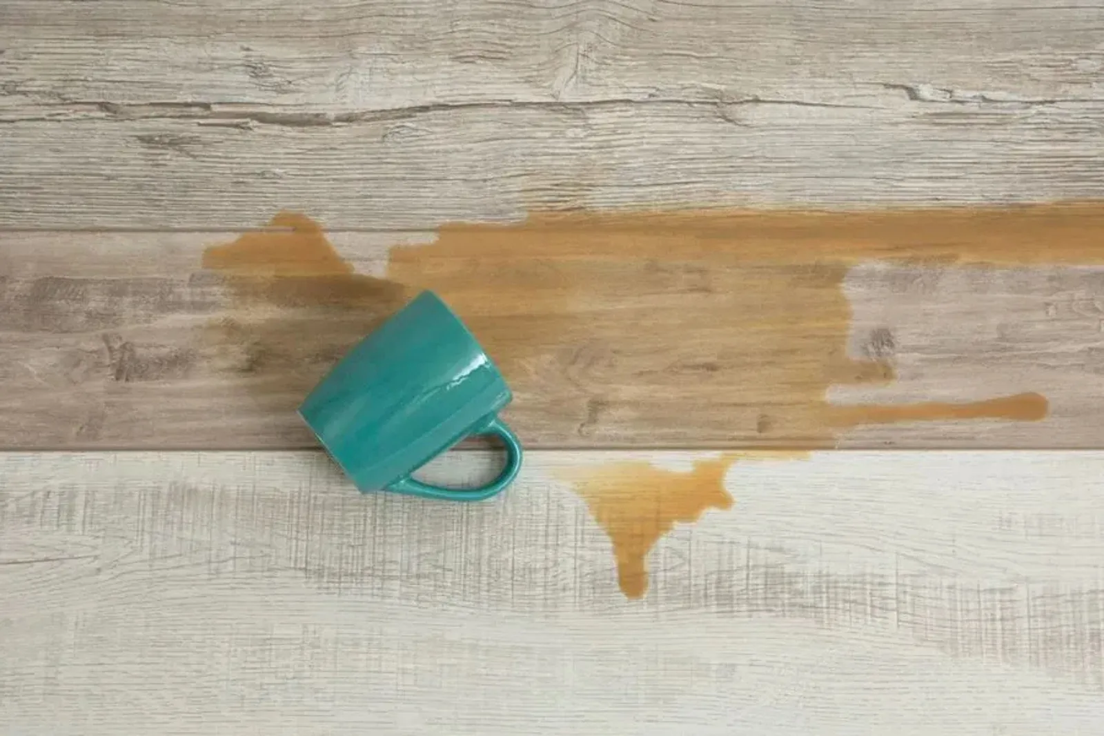 Spilled coffee on durable wood-look vinyl plank flooring, demonstrating the product's water-resistant and easy-to-clean qualities.