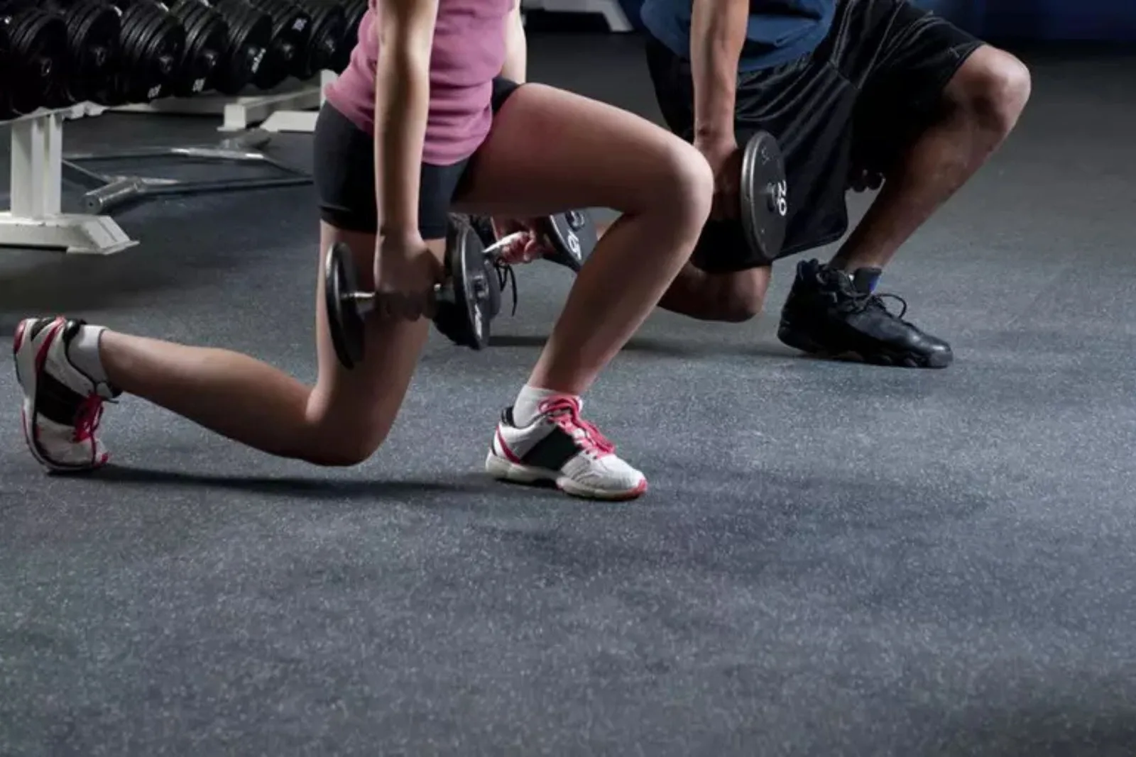 People exercising on durable gray speckled rubber gym flooring, a protective and high-performance solution for a weight room or fitness center.