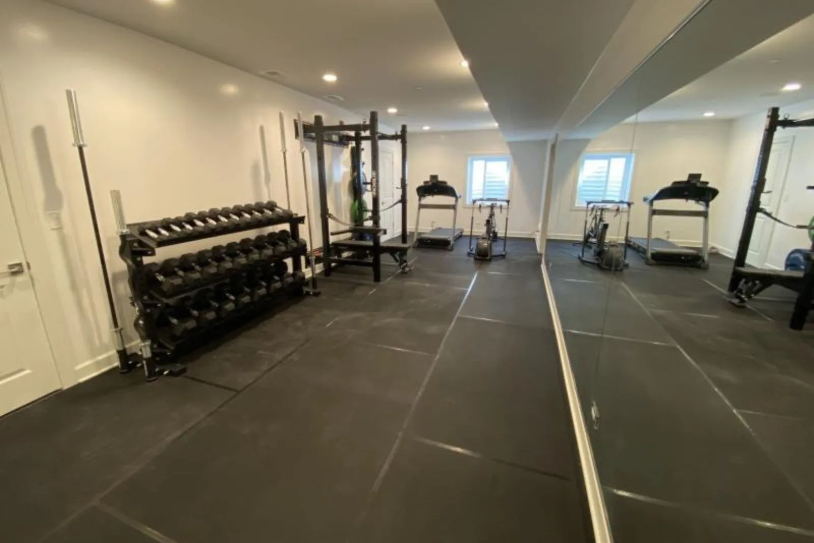 Home gym with durable black rubber interlocking gym floor tiles, a high-performance and protective flooring solution for residential workout spaces.