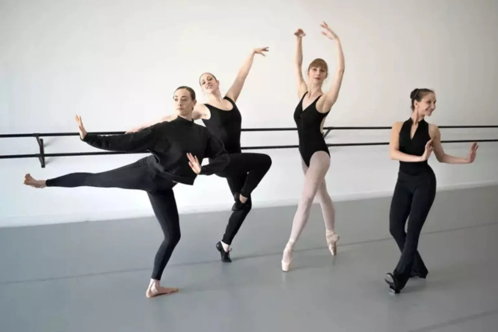 Four dancers in room with gray adagio tour rolls.