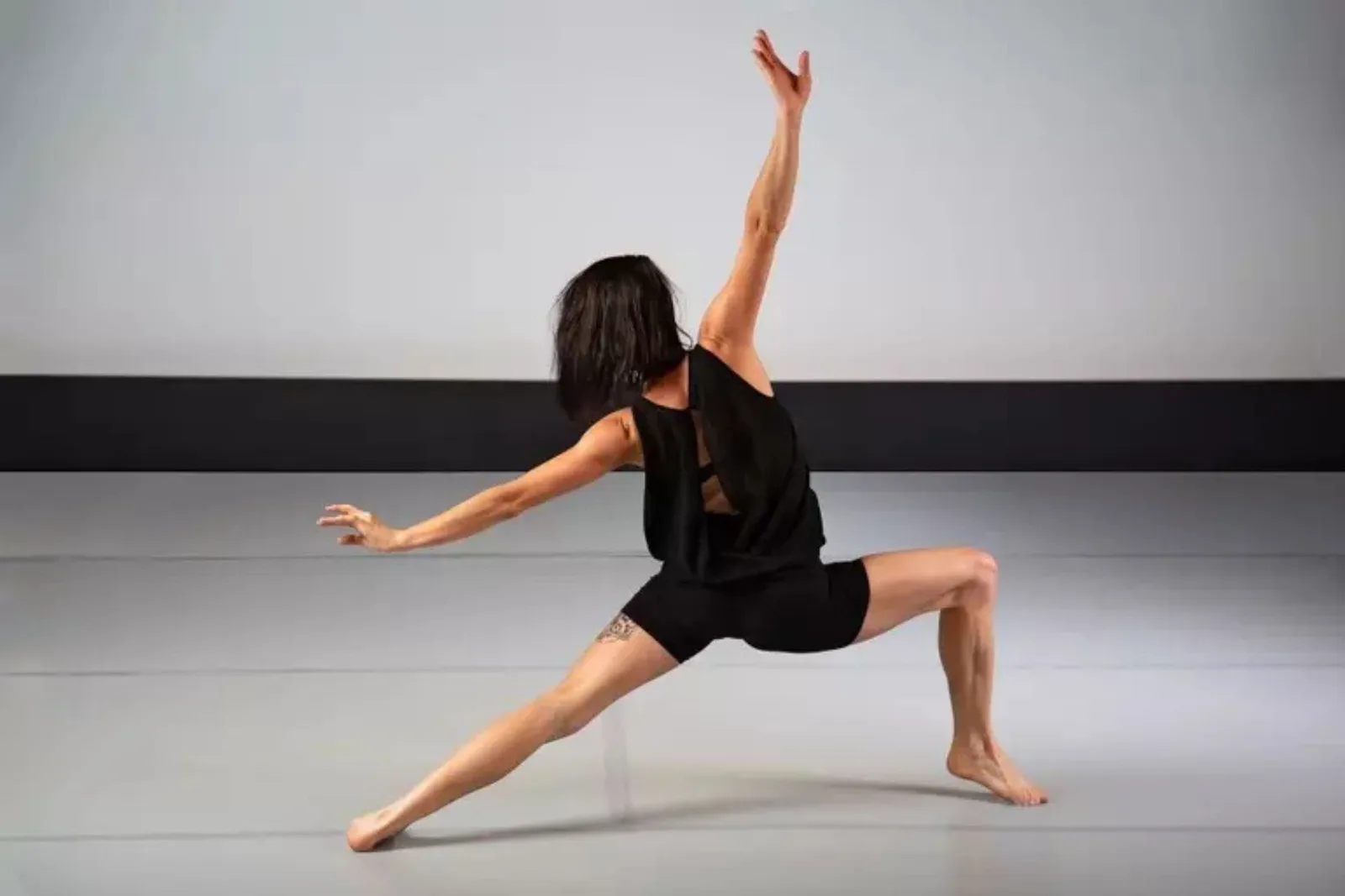 Dancer in studio on gray dance floor rolls.