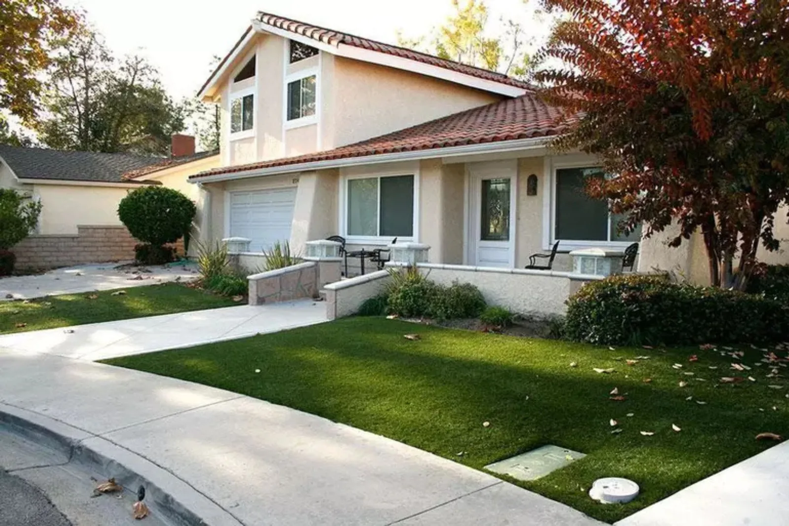 The front yard of a suburban home featuring a lush, manicured lawn of artificial turf. The residential synthetic grass provides a realistic, low-maintenance, and water-saving landscape solution, maintaining its green appearance year-round.