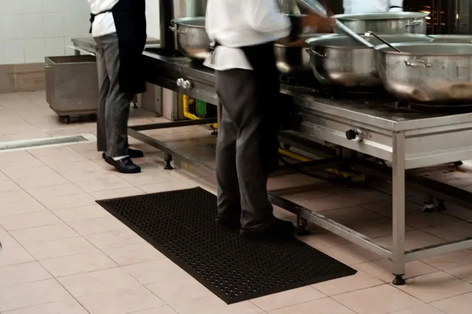 Commercial kitchen with a durable black anti-fatigue mat on tile flooring, a functional and safe solution for high-traffic food service environments.