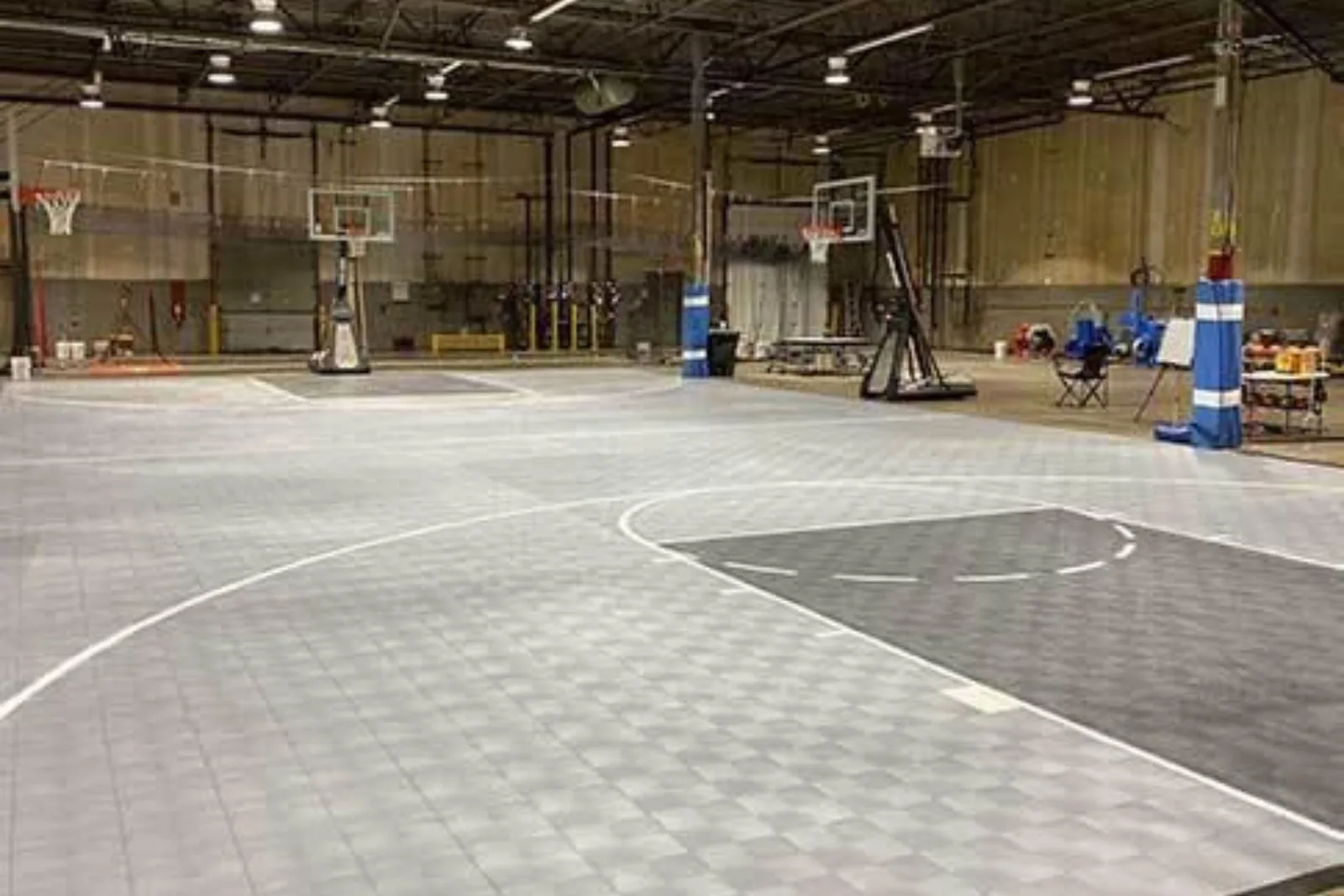 Indoor basketball court with durable gray and black sports tiles, a high-performance and easy-to-install flooring solution for a commercial gym.