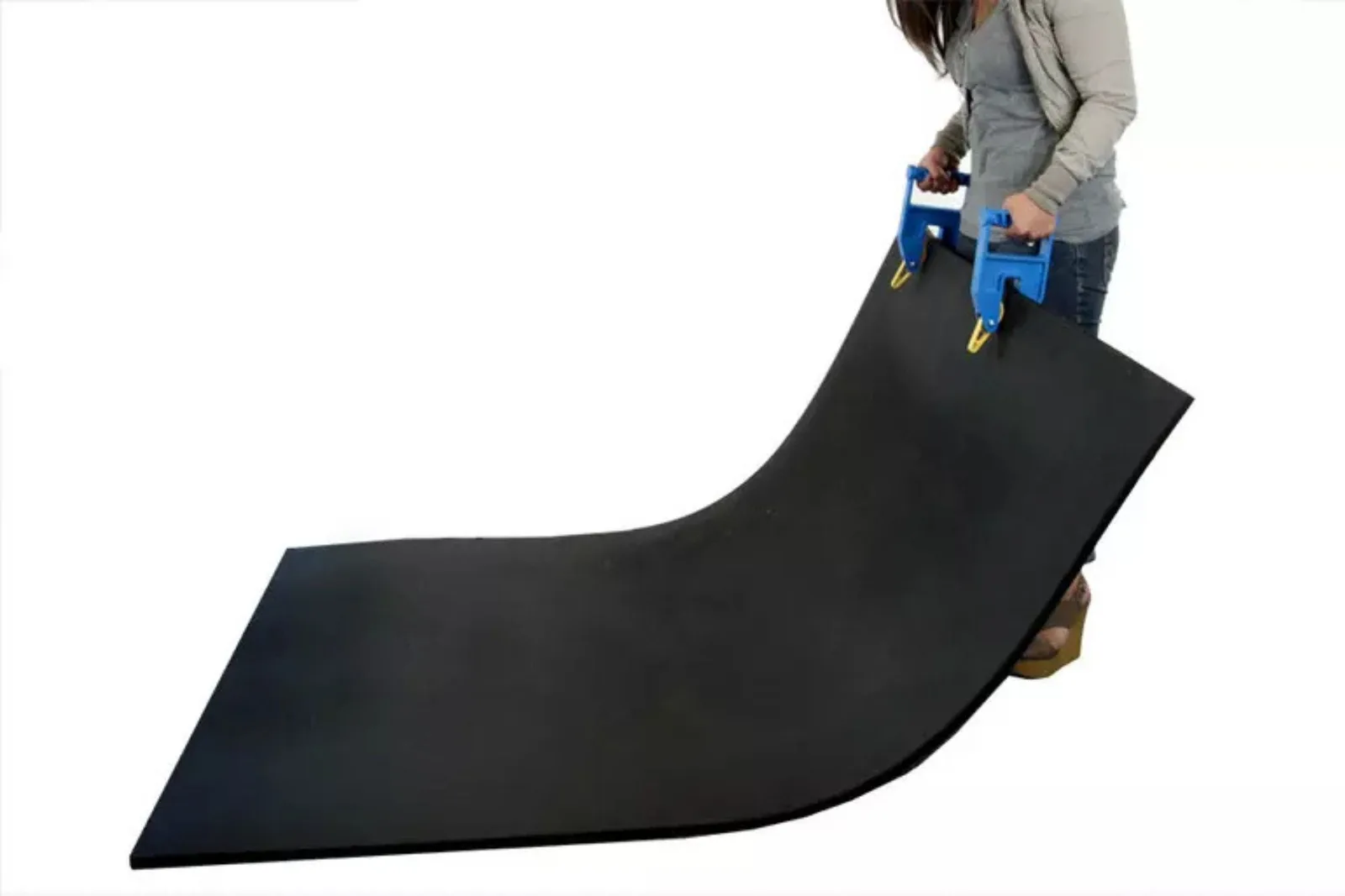 Person using a rubber mat carrying clamp to easily transport a large black gym mat, a useful tool for installing rubber flooring.
