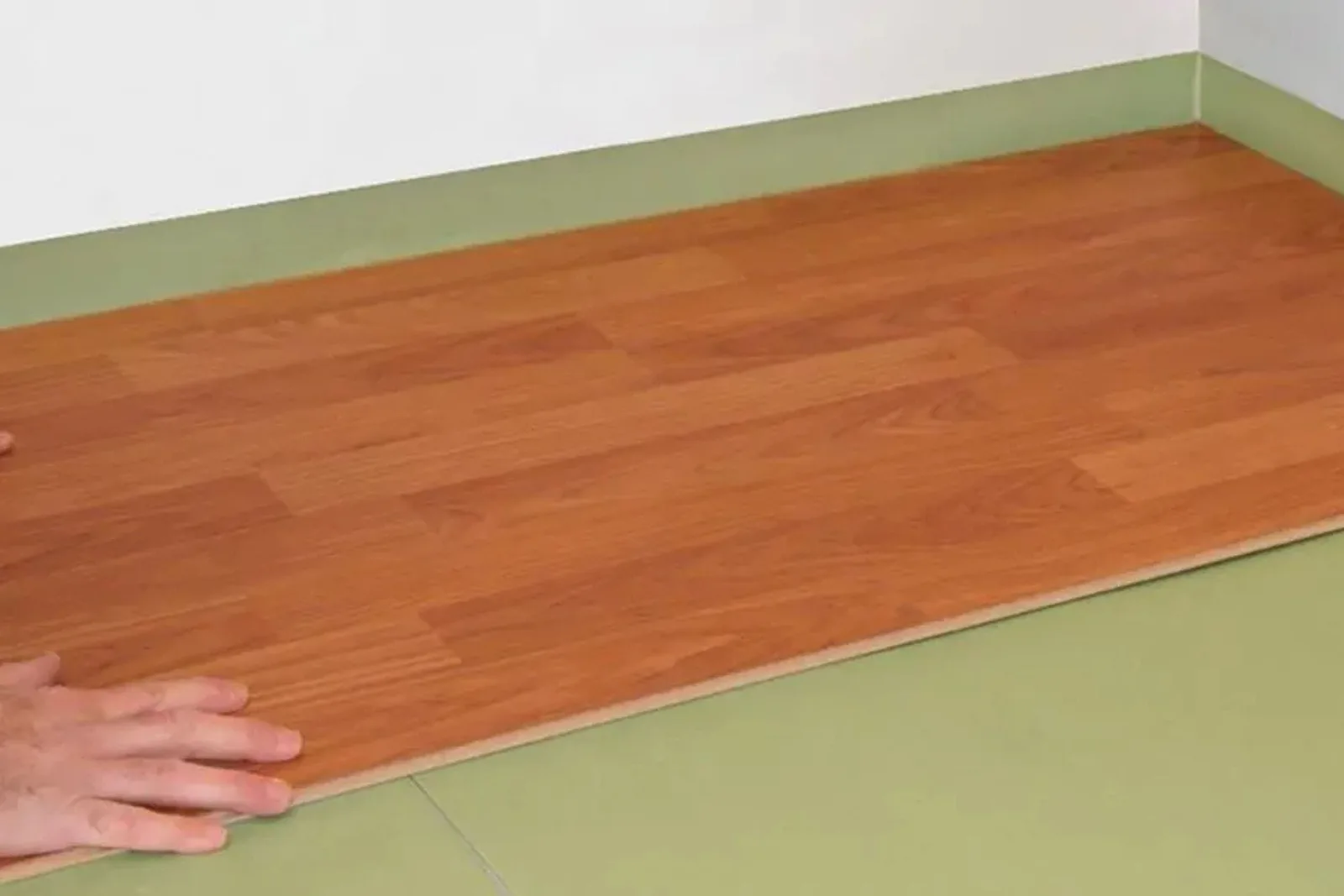 Person installing durable medium wood-look laminate flooring with a click-and-lock system, a simple and effective flooring solution for DIY projects.