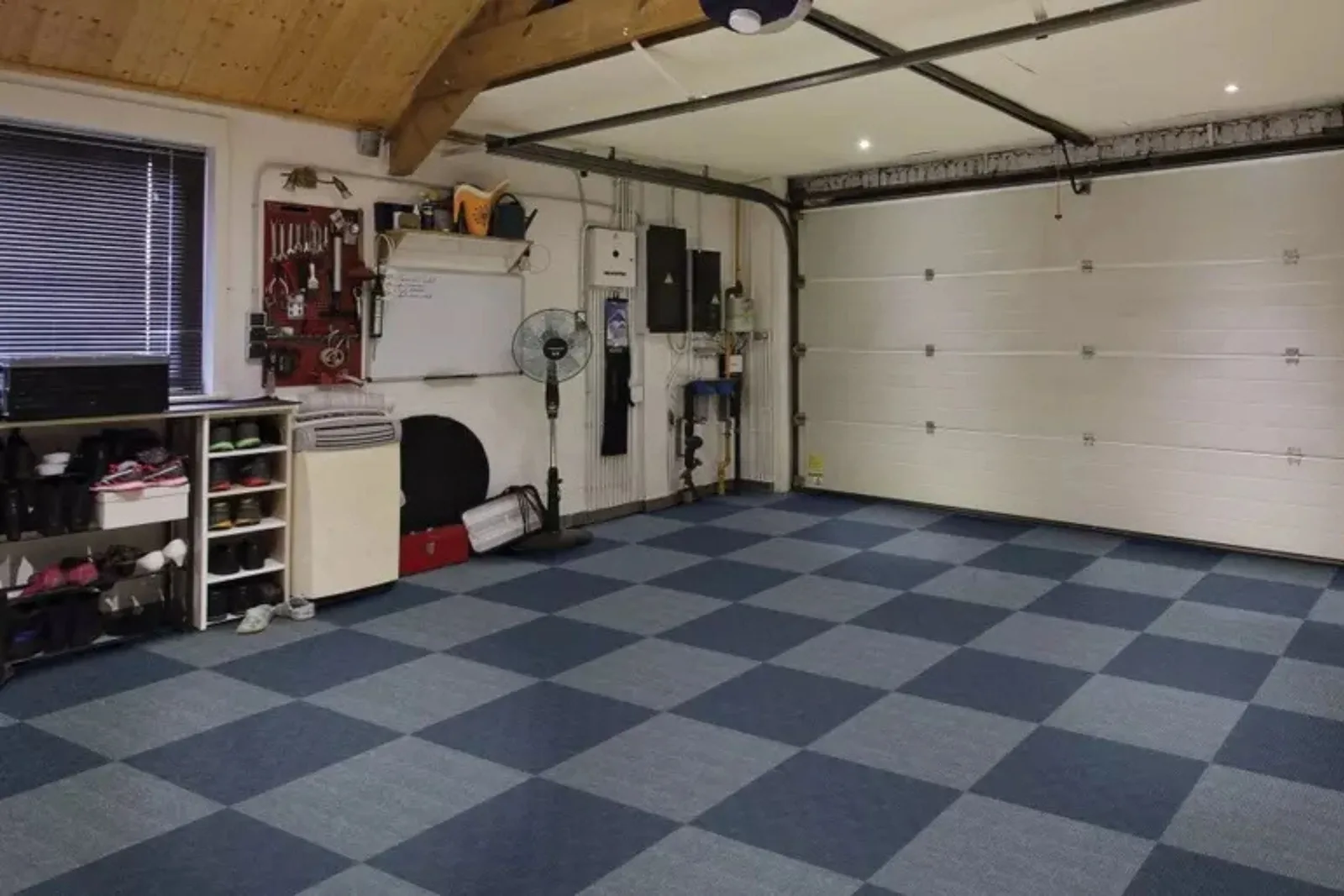 Blue checkerboard garage carpet tiles installed in a clean, organized workshop and storage space