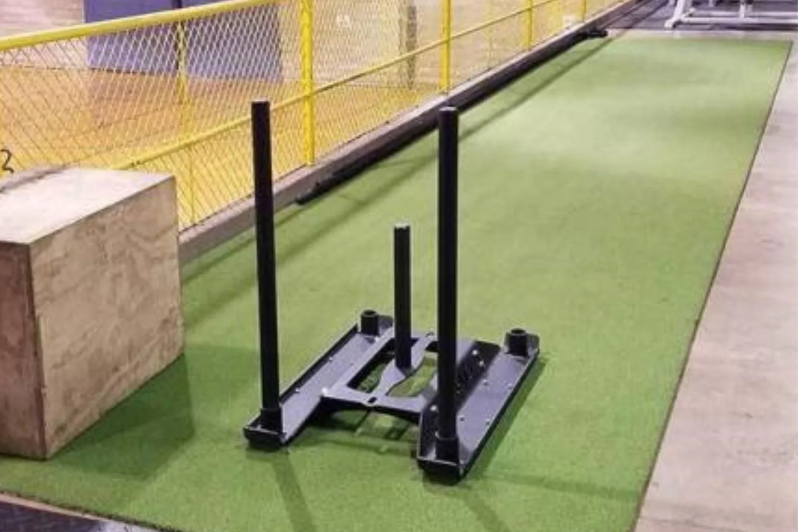 Indoor gym with a weight sled on durable green artificial turf, a high-performance and long-lasting flooring solution for athletic training spaces.