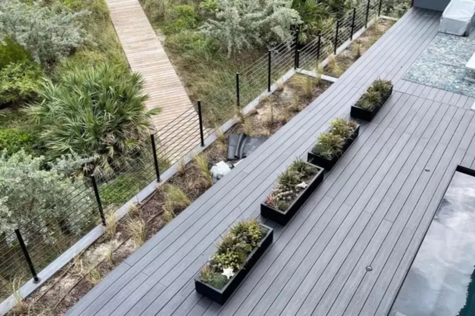 Composite decking boards in a modern gray finish create a low-maintenance and durable rooftop deck with planters and a stylish outdoor living space.