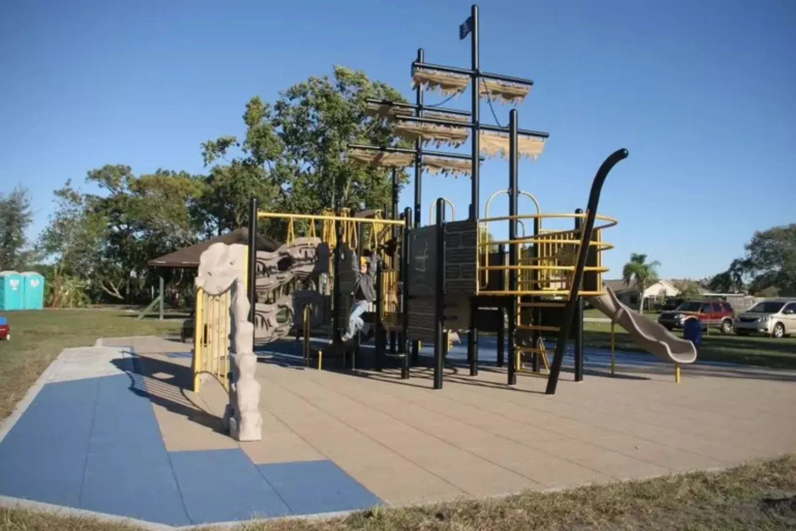 Rubber Playground Tiles Durable rubber playground tiles in a park with a pirate ship-themed playset, creating a safe, cushioned, and impact-absorbent playground flooring for kids.