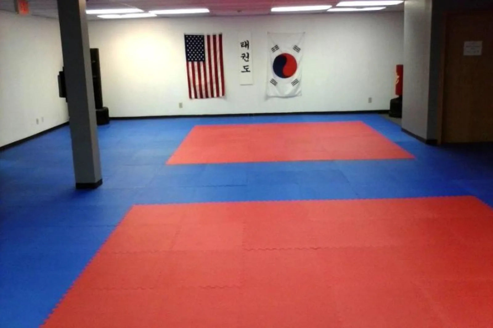  Interlocking foam tile flooring in a blue and red pattern creates a safe and shock-absorbent martial arts mat flooring surface for a Taekwondo studio.