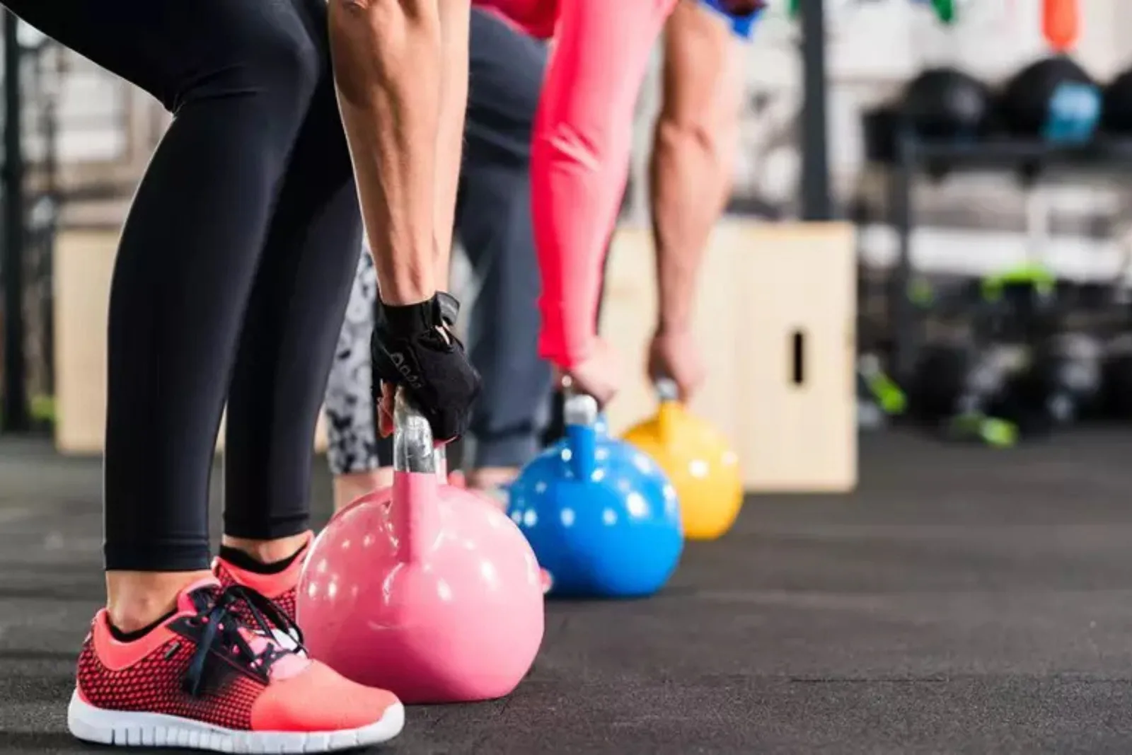 Durable black rubber gym flooring Close-up of people performing kettlebell swings or deadlifts on durable black rubber gym flooring, a protective and non-slip surface for functional fitness.