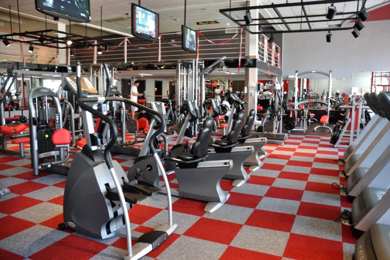 Durable red checkered carpet tiles Spacious commercial gym with durable red and gray checkered carpet tiles, providing a comfortable and bold, high-traffic flooring solution.