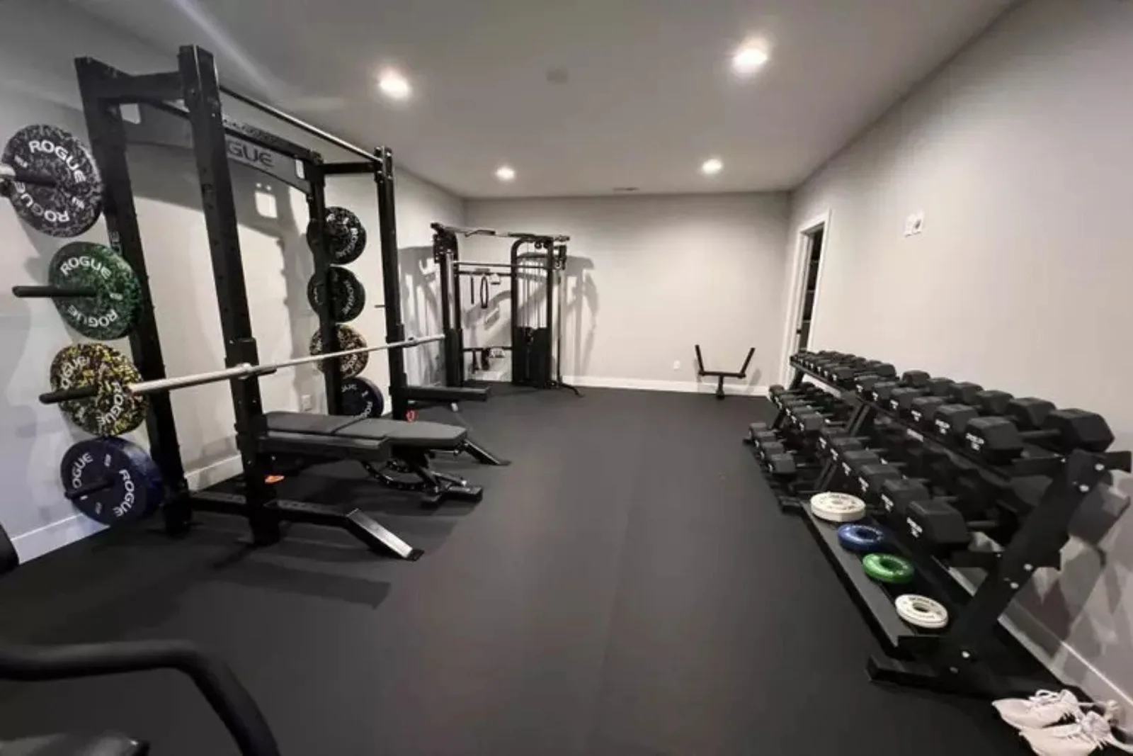 Durable black rubber gym flooring Modern home gym featuring a squat rack and dumbbell racks on durable black rubber gym flooring, providing a protective and high-performance workout surface
