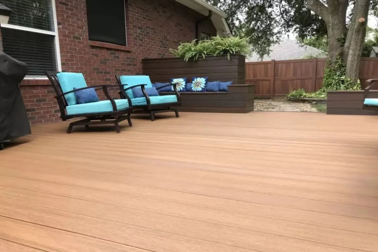 Wood grain composite decking deck boards create a beautiful, low-maintenance, and professional outdoor patio surface in a residential backyard.