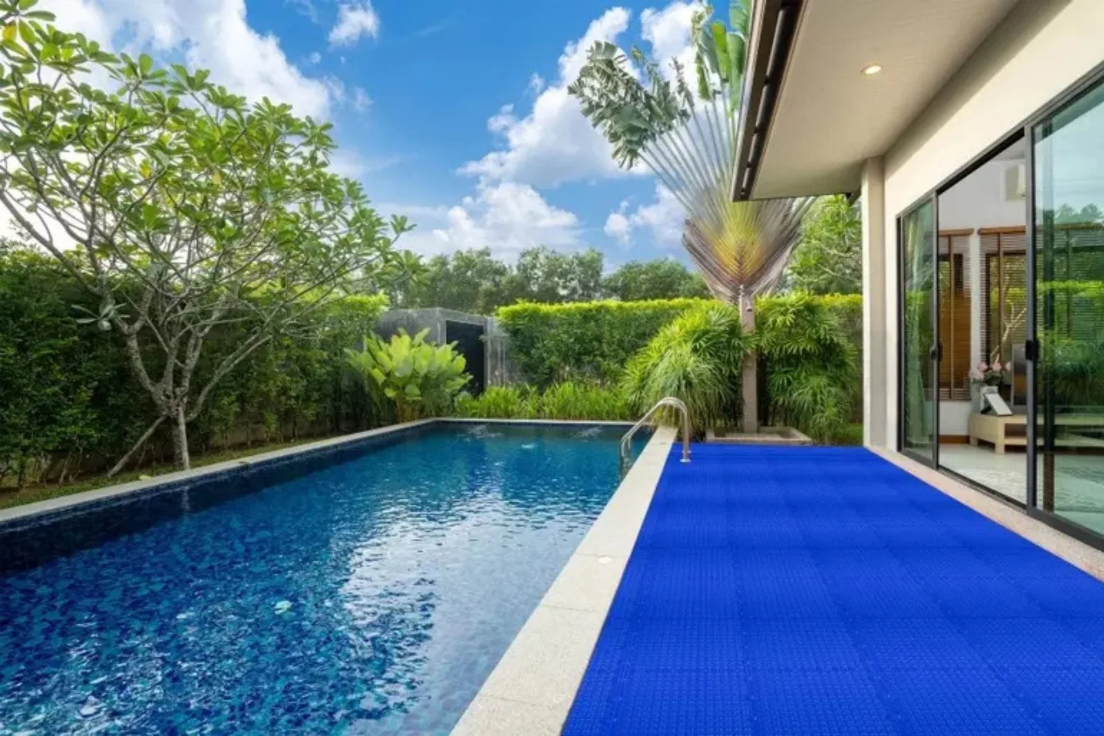 Vented PVC interlocking drainage tiles in bright blue create a safe, slip-resistant, and quick-drying poolside flooring in an outdoor residential setting.