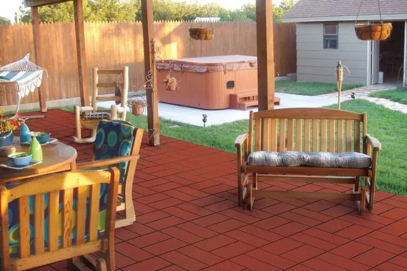 Durable interlocking rubber deck tiles in a brick red pattern, creating a cushioned and slip-resistant outdoor flooring in a living space with a patio table and chairs, and a hot tub.