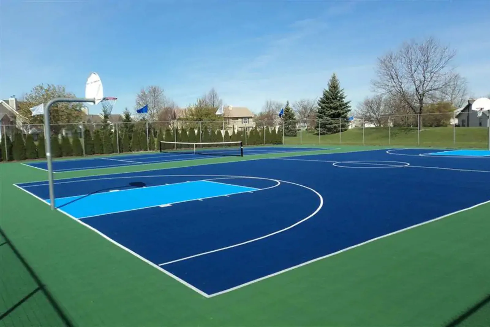 Outdoor basketball court tiles in blue and light blue, creating a vibrant, low-maintenance, and professional-looking multi-use court in a residential setting.