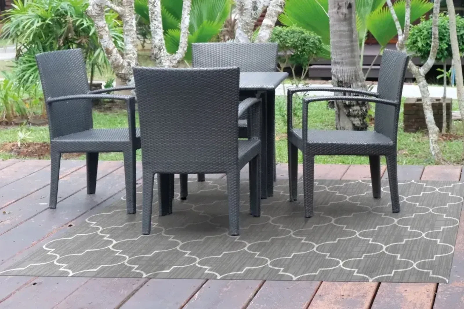 Outdoor patio rug in a gray geometric pattern, providing a stylish and comfortable accent for a wooden deck with outdoor furniture.