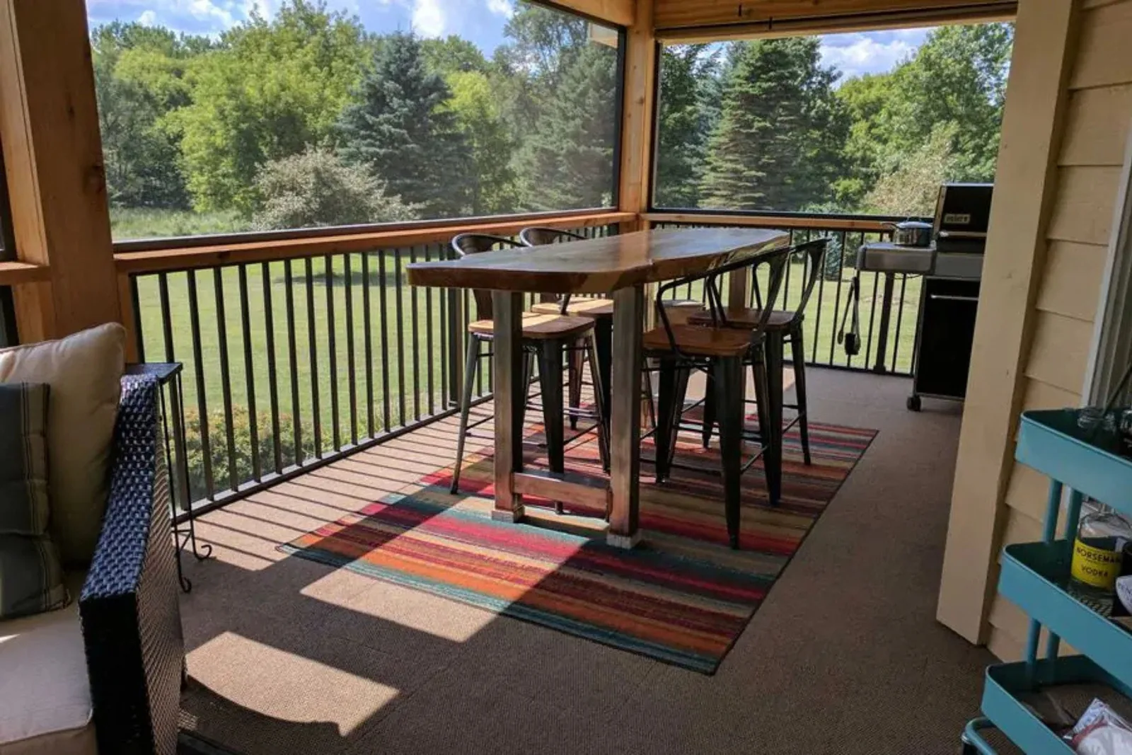 Durable outdoor rug in a colorful striped pattern on a screened-in porch, creating a stylish and comfortable accent under a dining table and chairs.