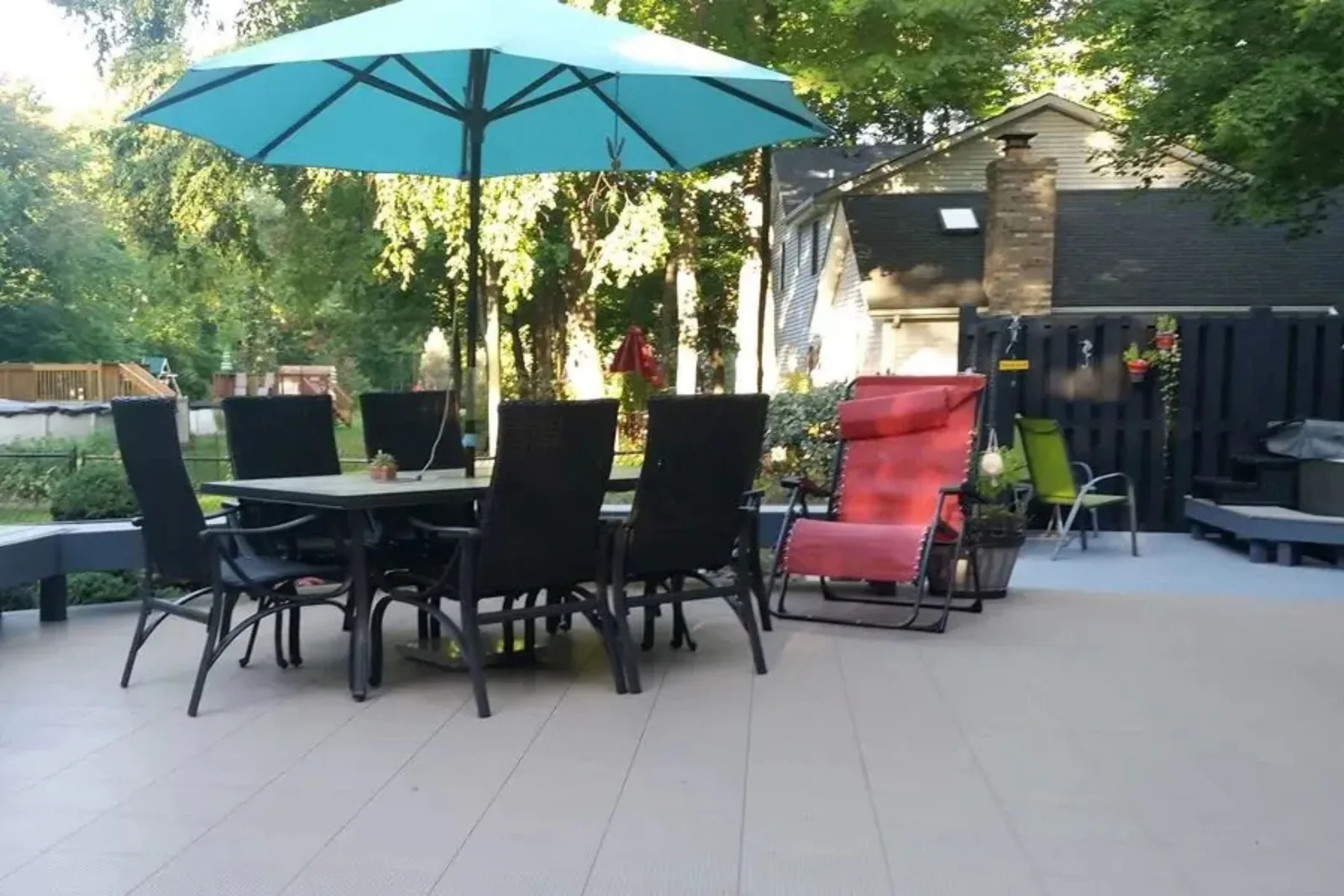Patio dining set and umbrella on beige deck tiles