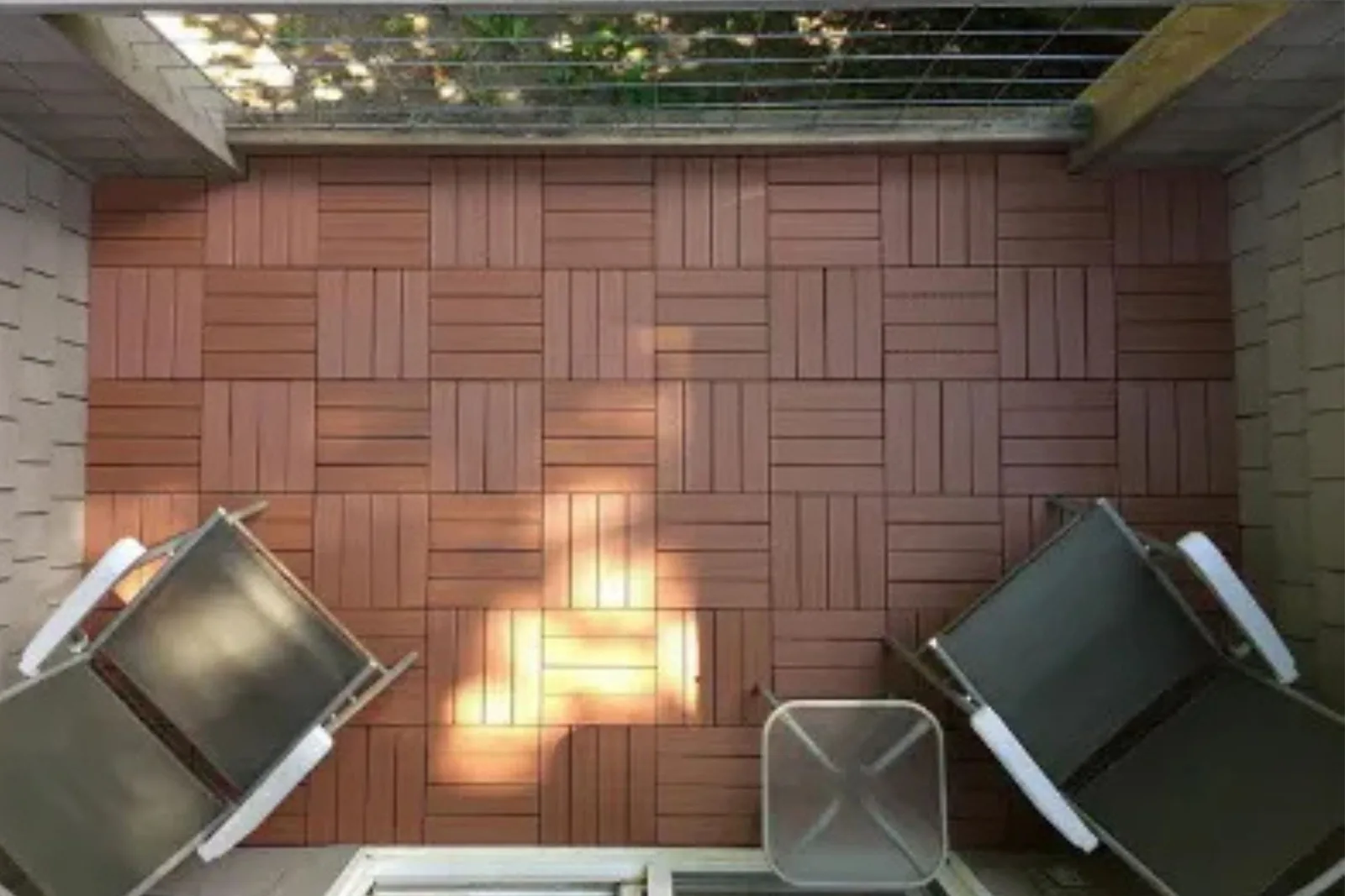 Composite deck tiles in a rustic wood finish create a warm and inviting outdoor flooring solution on a small balcony or patio.