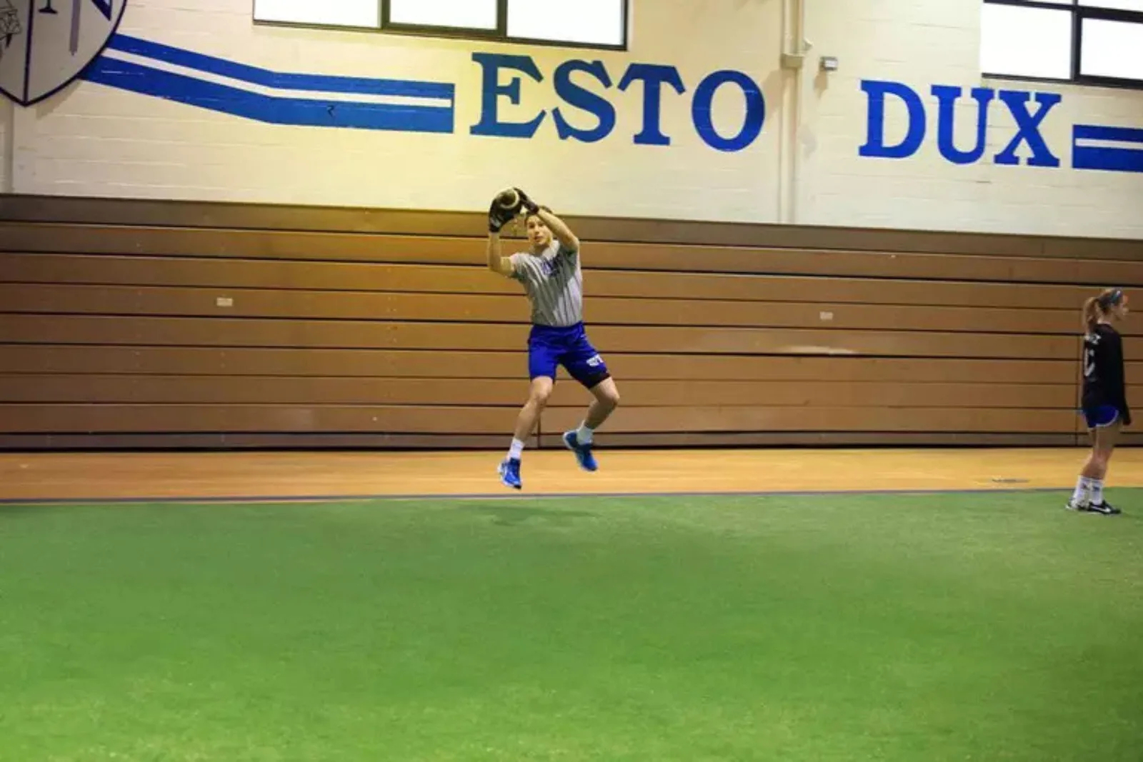 Indoor field turf provides a durable and all-weather surface for a school gym, with an athlete jumping to catch a football during practice.