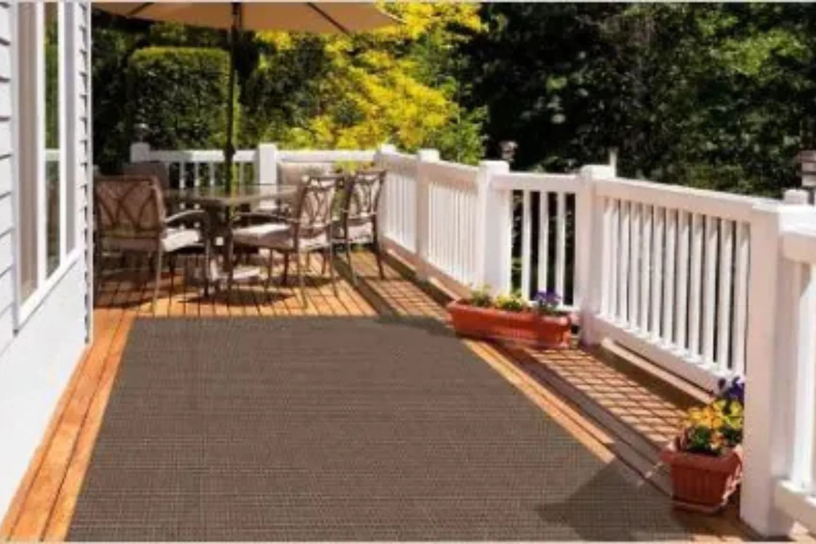 Outdoor wooden deck with a durable solid brown area rug, a perfect and stylish, weather-resistant flooring solution.