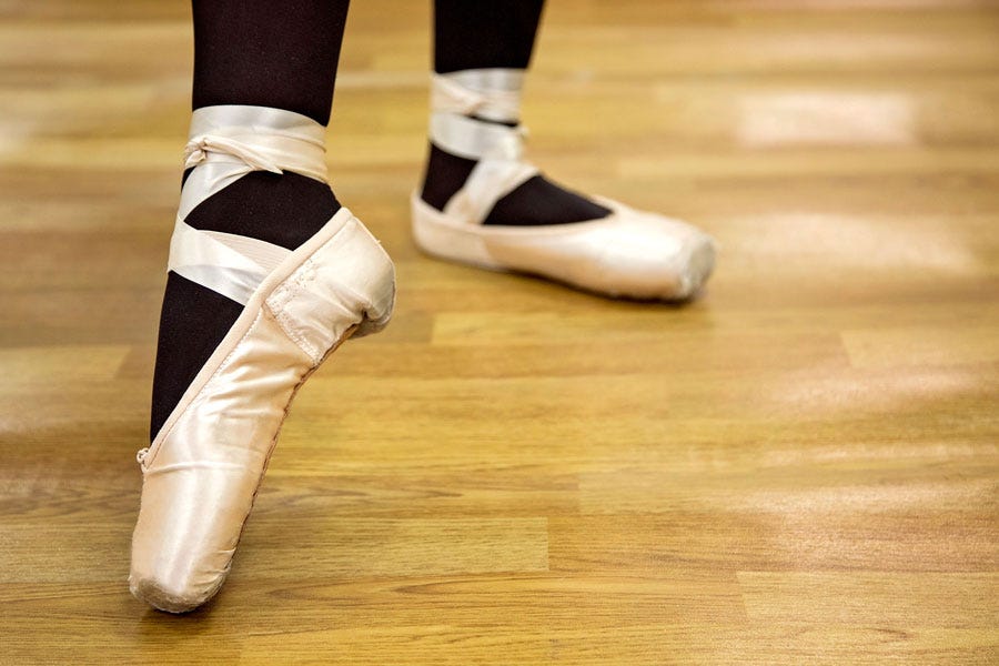 a ballet dancers feet on wood dance flooring