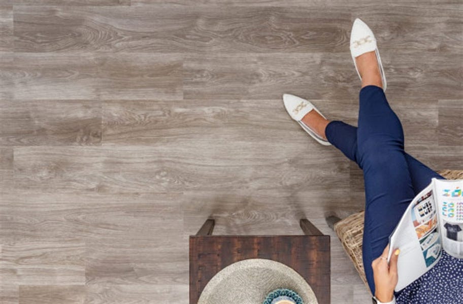 Woman reading magazine on American made wood flooring. Featured: Swiss Krono