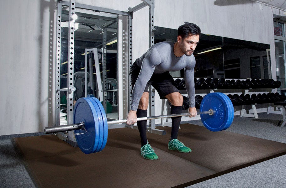 Weight-lifter using rubber mat flooring in a gym setting
