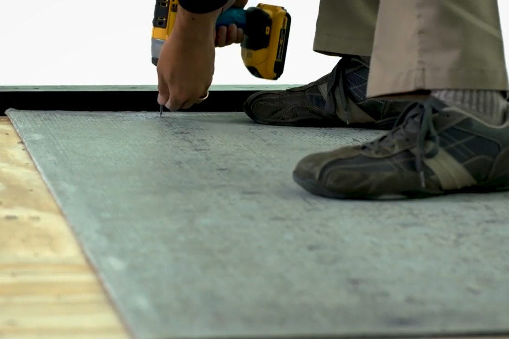 Securing a cement backer board to a plywood subfloor for tile installation prep.