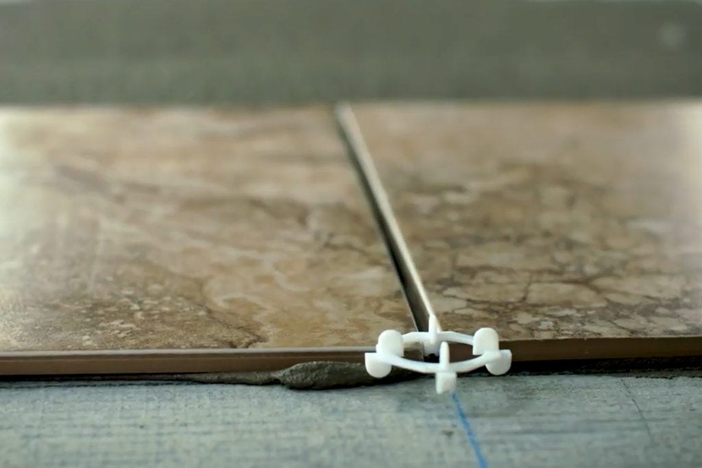 Close up view of laying ceramic floor tile into thinset
