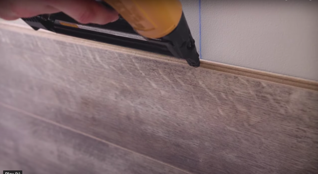 Install laminate planks on the wall by securing them with nails