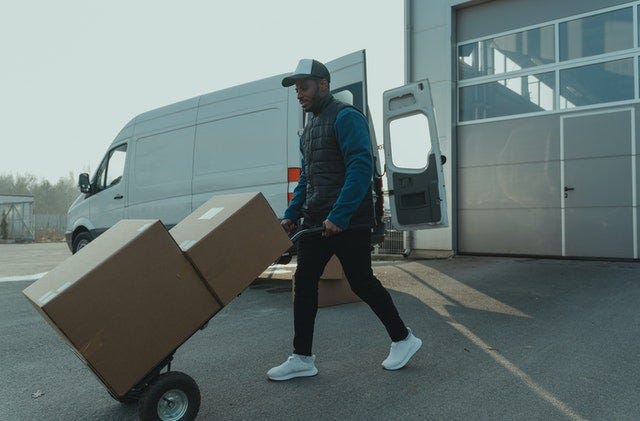 A person pushing a dolly with boxes on it