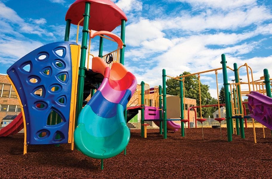 Playground Rubber Mulch pictured underneath a rainbow colored slide. 