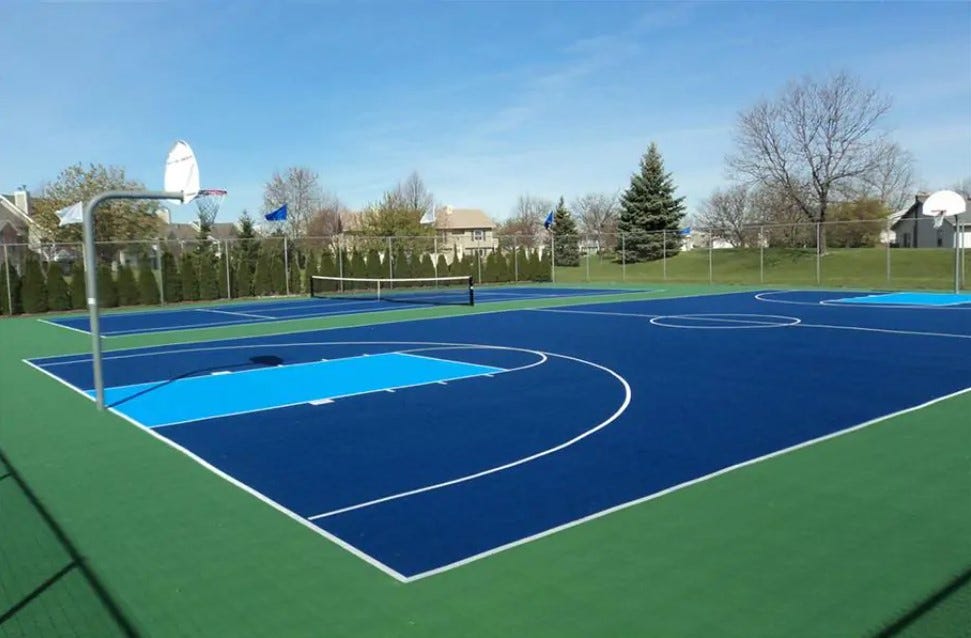 a blue and green tennix and basketball court in a residential park