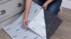 a person using peel and stick carpet tiles